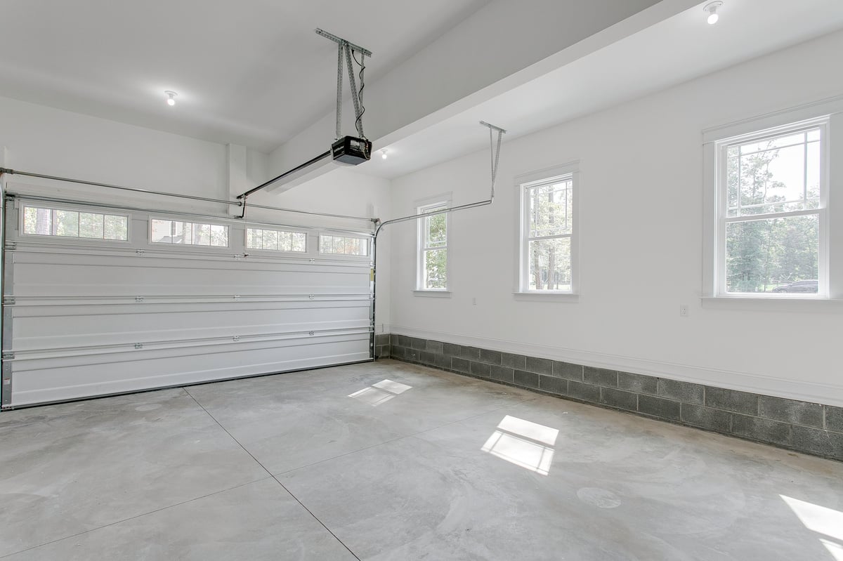 A clean, bright garage with overhead doors and natural light filtering through the windows